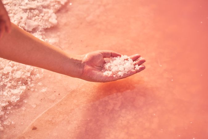 Female holding healing salt pile in pink water