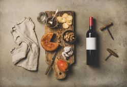 Cheese plate with red bottle of wine, linen towel, and corkscrews
