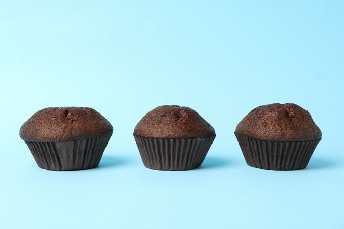 Delicious tasty chocolate muffins on blue background