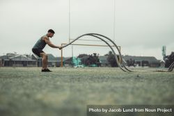 Athlete working out with battle ropes outdoors on grass field 0LrJR4