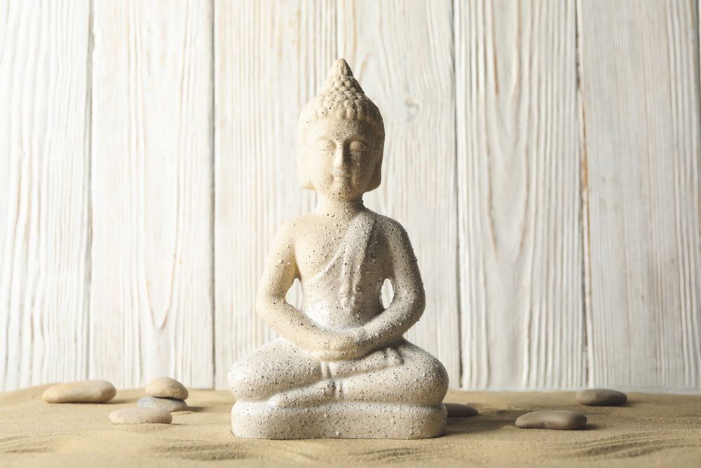 Buddha on sand against wooden background. Zen concept
