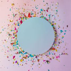 Party confetti surrounding blue circle on pink background