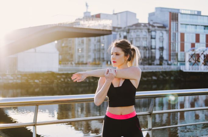 Woman stretching on embankment near water
