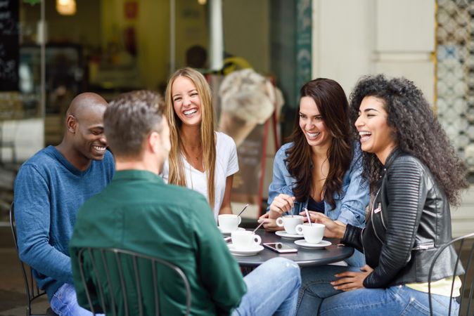 Multi-ethnic group of five friends socializing over coffee