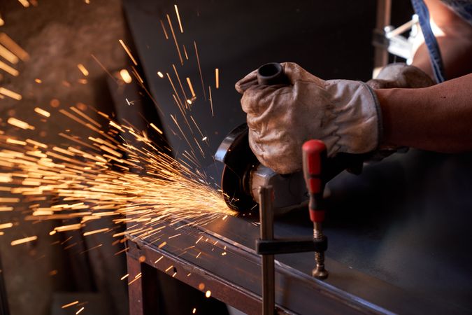 Crop man doing metalwork with angle grinder