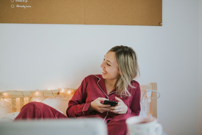 Woman sitting in bed with tablet and looking on smartphone