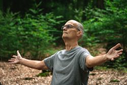 Older man meditating in forest