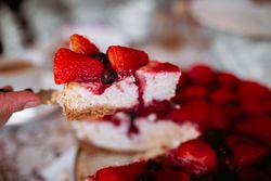 woman's hand cutting strawberry cake with knife