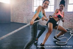Shot of two young women smiling while exercising with rope at a gym 0yqE10