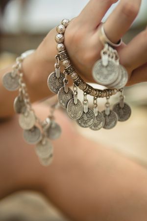 Woman wearing silver coin charm bracelets and ring