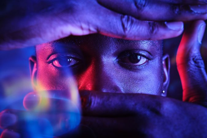 Crop Black man looking at camera through camera hand gesture