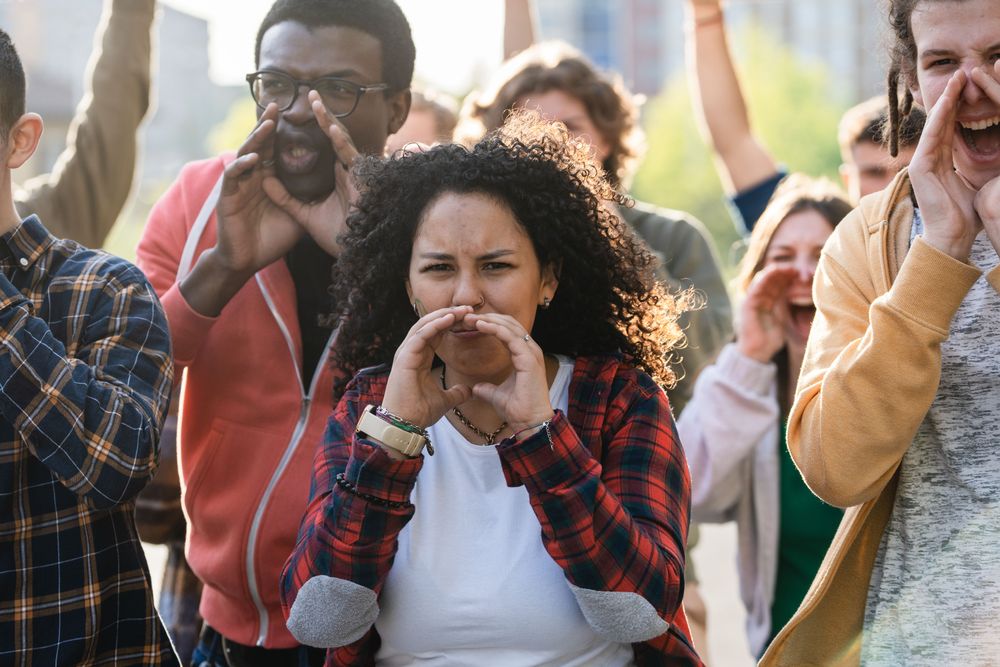 A group of young activists, passionately yelling and voicing their concerns during a protest in the city