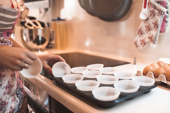 Cropped image of woman preparing paper cups for muffins