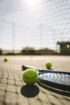 Ground level shot of a tennis racket with balls on tennis court