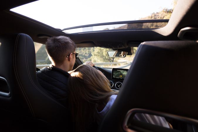 Woman leaning on boyfriend as he drives vehicle