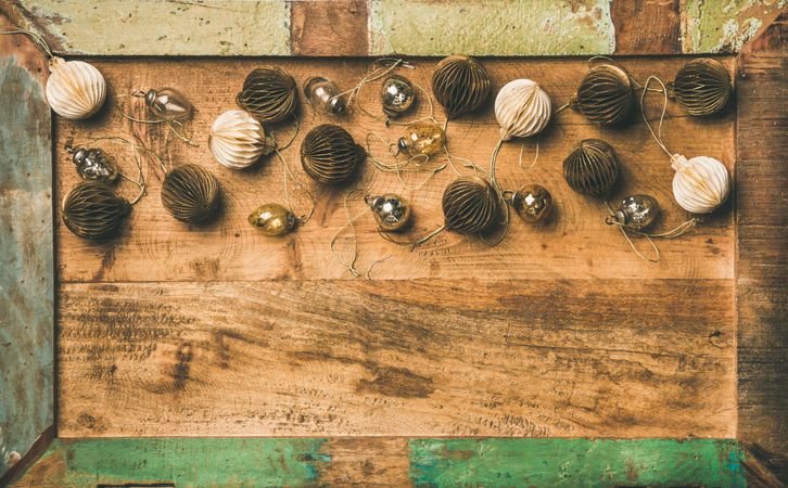 Gold and cream folded tree ornaments, and baubles on wooden counter, copy space