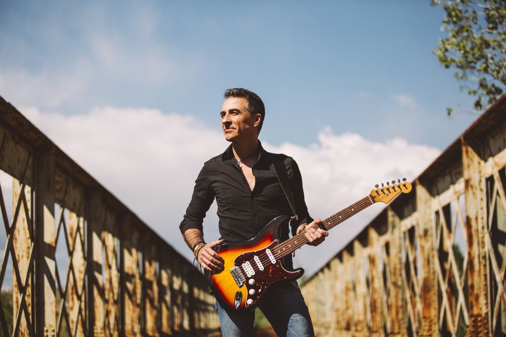 Man with guitar standing on bridge