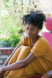 Woman sitting in chair hugging her legs looking away from camera contentedly