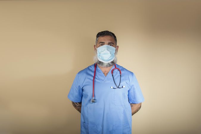 Doctor with facemask standing against yellow background
