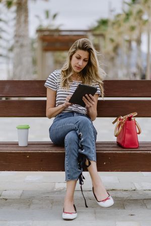 Woman sitting on bench and using tablet