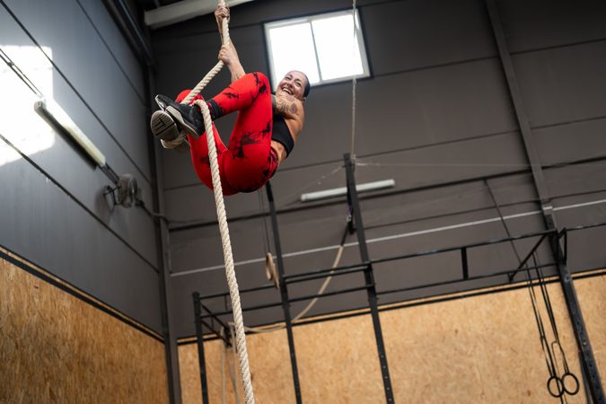 Woman climbing a rope exercising in a cross training center