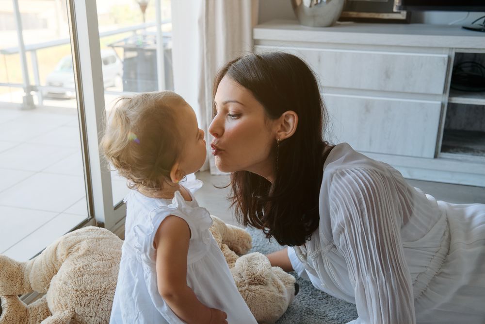 Young mother kissing daughter at home
