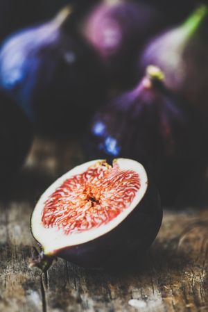 Figs, one halved, on wooden cutting board, close up