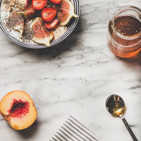 Flat-lay of yogurt bowl with fruit, honey and spoon, square crop, copy space