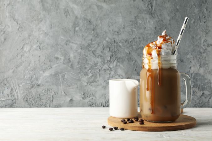 Iced coffee with poured cream on wooden background
