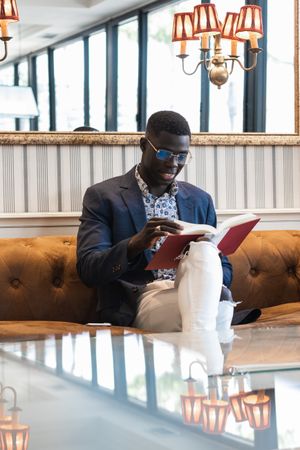 Pensive Black businessman reading book in cafe