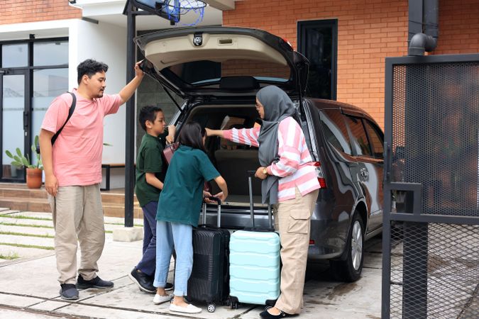 Indonesian Young Family Preparing for Trip in front of Their House, with Suitcases