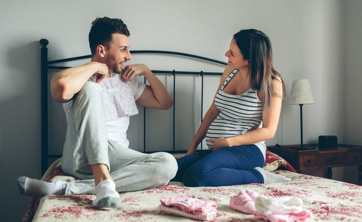 Man showing baby clothes to pregnant woman