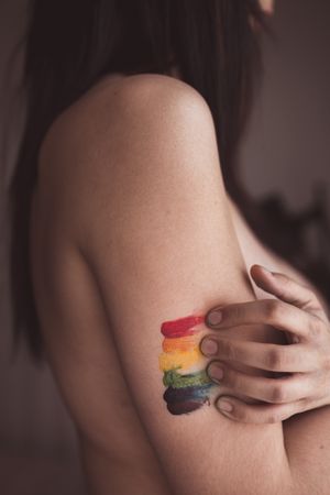 naked woman covering breast and drawing LGBTQIA symbol