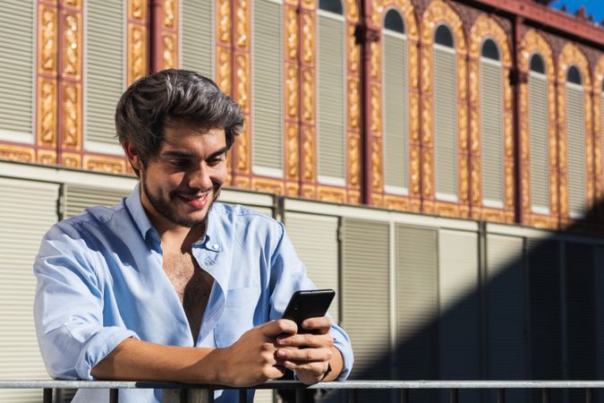 Smiling man browsing mobile phone in city