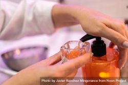 Female hands pumping cream into glass 5qk9lo