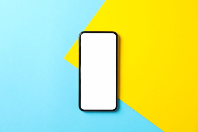 Phone with empty screen on two tone background, top view