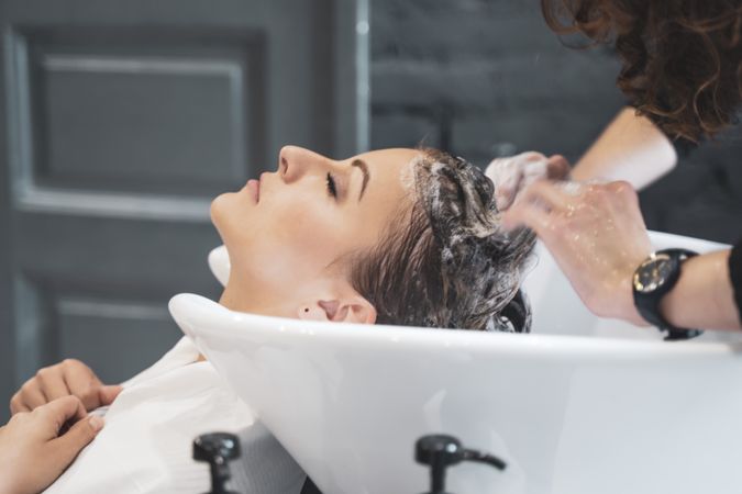Stylist washing hairs to young lady