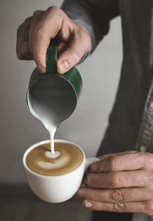 Man pouring milk in cappuccino or latte