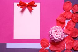 Blank paper note with bow and petals with copy space