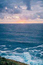 Grassy shore near stormy sea in evening
