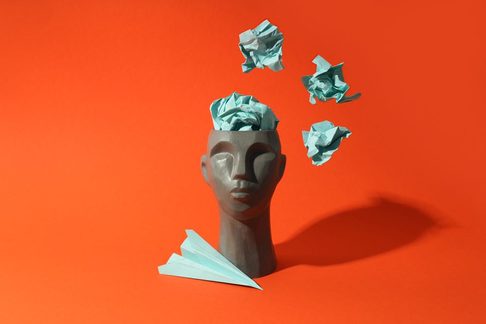 Grey bust of head on red background with crumpled paper