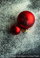 Christmas card concept with two red baubles on snowy table, vertical composition bD7mA4