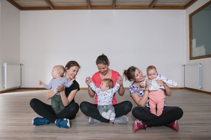 Mothers lifting babies in gym
