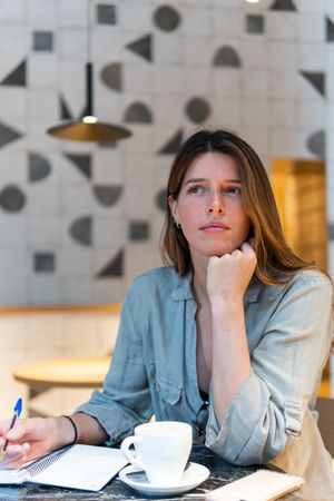 Dreamy woman with notebook and tea in cafe