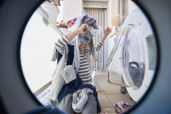 Boy playing with clothes in laundry room
