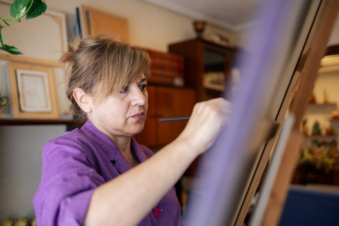 Adult woman painting canvas at home