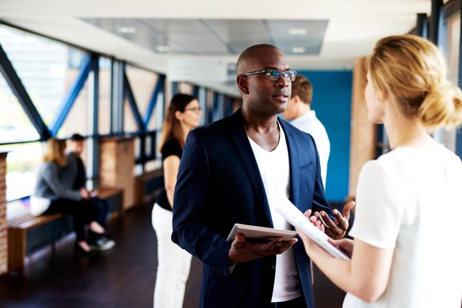 Businessman discussing plans with his female colleague in an office corridor