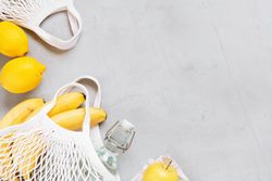 Yellow fruits in mesh back on grey table, copy space