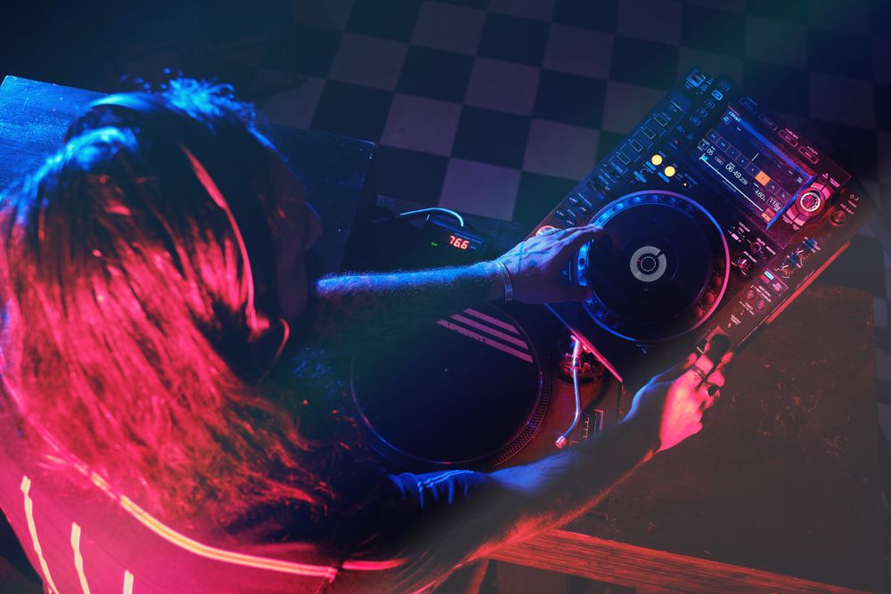 Faceless DJ in headphones playing song in club