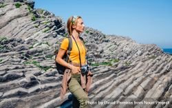 Woman enjoying view on an ocean hike with a camera 0Pr3l4